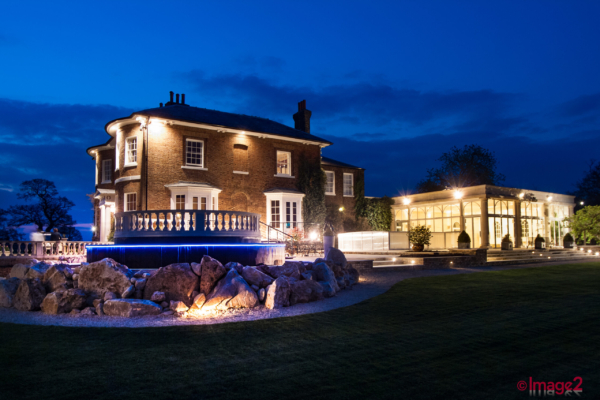 Architectural photograph of luxury home at night. An existing house with added glass building