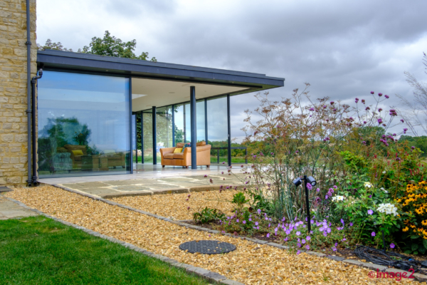 Farmhouse with a modern glass extension on hill giving excellent views.